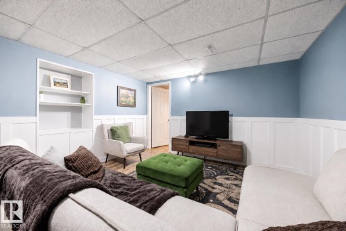 Finished room featuring light blue walls with white wainscoting, a built-in shelving unit, and wood-finish flooring - 17932 93 Avenue, Edmonton, AB 