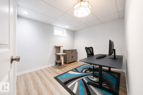 Versatile room featuring light wood-finish flooring, recessed lighting, and a drop ceiling - 17932 93 Avenue, Edmonton, AB 