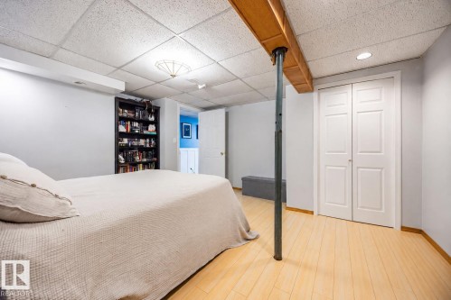 Lower-level room featuring light wood-finish flooring, a suspended ceiling, and a prominent wood beam - 17932 93 Avenue, Edmonton, AB 