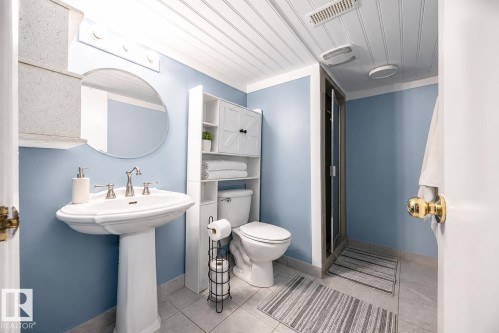 Pedestal sink with dual-handle faucet, circular wall mirror, and vanity lighting - 17932 93 Avenue, Edmonton, AB 