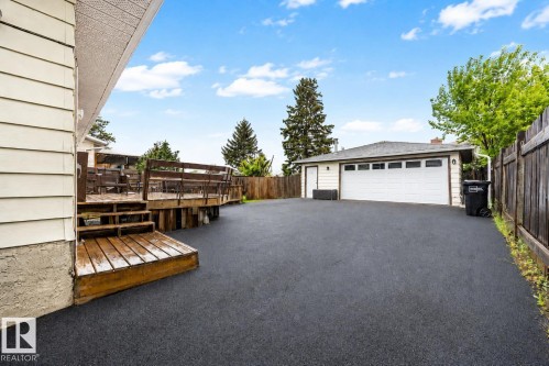 Spacious asphalt driveway providing access to a detached garage with a white overhead door and side entry - 17932 93 Avenue, Edmonton, AB 