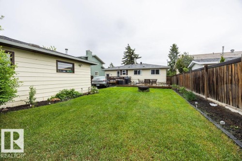 Expansive green lawn with a perimeter garden bed, leading to a wooden deck - 17932 93 Avenue, Edmonton, AB 