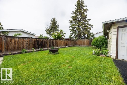 Expansive green lawn area featuring a fire pit and perimeter wood fencing - 17932 93 Avenue, Edmonton, AB 