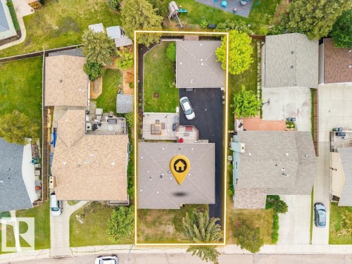 Aerial overview showcasing a property with a distinct, elongated lot featuring a primary residence, a detached garage, and a substantial paved driveway - 17932 93 Avenue, Edmonton, AB 