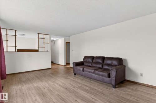 Spacious room featuring wood-finish flooring, light-toned walls, and a textured ceiling - 13920 64 Street, Edmonton, AB 