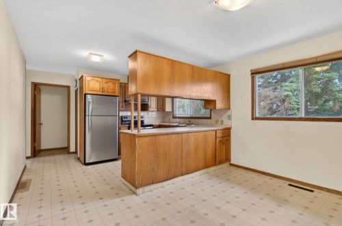 Kitchen area featuring wood cabinetry, stainless steel appliances, and a window with exterior views - 13920 64 Street, Edmonton, AB 