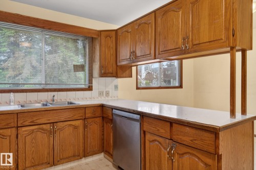 Kitchen featuring wood-finish cabinetry, white countertops, and a double basin sink - 13920 64 Street, Edmonton, AB 