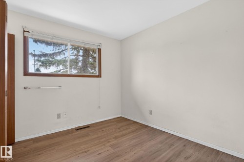 Interior room featuring wood-finish flooring, white painted walls, and a window with a wood frame and blinds - 13920 64 Street, Edmonton, AB 