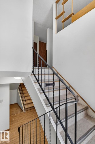Multi-level interior featuring a staircase with black metal railings and light-colored steps - 13920 64 Street, Edmonton, AB 