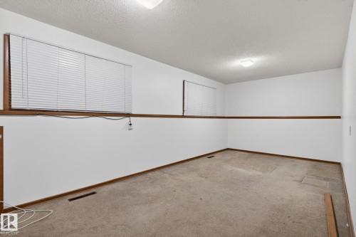 Finished room featuring two windows with horizontal blinds, white walls, wood trim, and carpeted flooring - 13920 64 Street, Edmonton, AB 