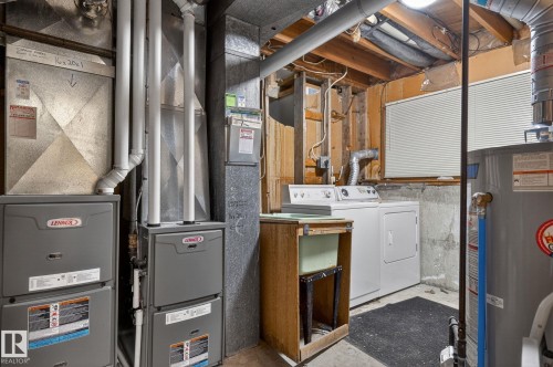 Utility area featuring two Lennox furnaces, a hot water heater, and a laundry station with a washer, dryer, and utility sink - 13920 64 Street, Edmonton, AB 