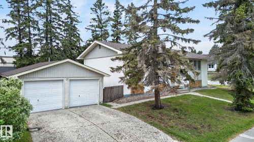 Contemporary home with white siding, a two-car garage with panel doors, and a concrete driveway - 13920 64 Street, Edmonton, AB 