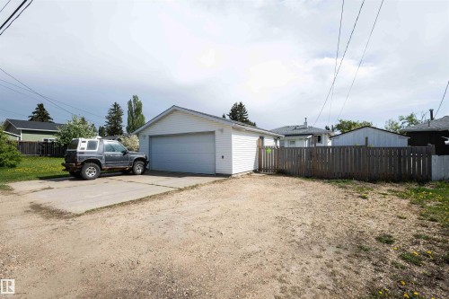Detached garage featuring white siding, a single overhead door, and a concrete driveway pad - 4414 54 Avenue, Barrhead, AB - Outdoor