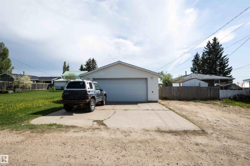Detached garage with white siding, a single overhead door, and a concrete driveway - 4414 54 Avenue, Barrhead, AB - Outdoor