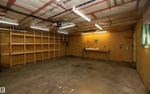 Spacious garage featuring concrete flooring and exposed ceiling rafters - 4414 54 Avenue, Barrhead, AB - Indoor Photo Showing Garage