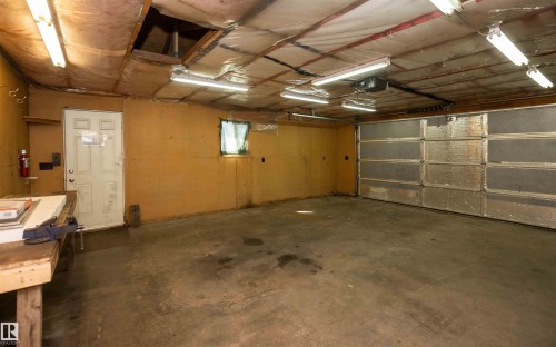 Spacious garage featuring a concrete floor, overhead fluorescent lighting, and an insulated garage door - 4414 54 Avenue, Barrhead, AB - Indoor Photo Showing Garage