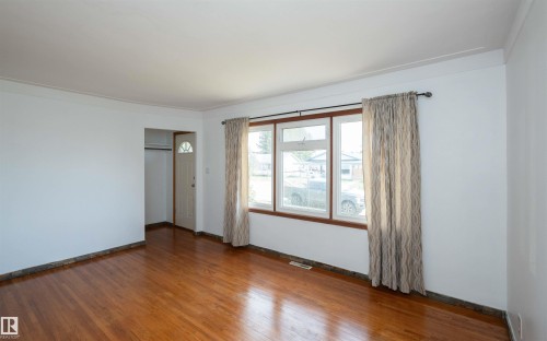 Hardwood flooring throughout featuring a large picture window with wood trim - 4414 54 Avenue, Barrhead, AB - Indoor Photo Showing Other Room
