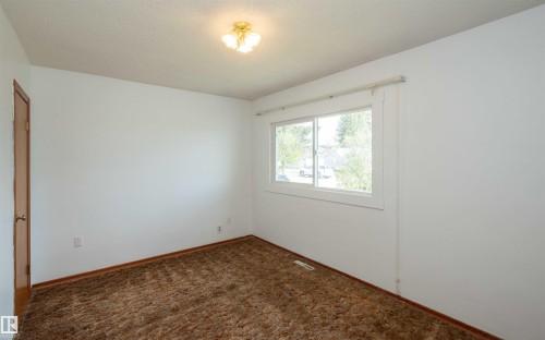 Bright room featuring a window with white trim, a flush-mount ceiling light fixture, neutral white walls, and brown carpet flooring - 4414 54 Avenue, Barrhead, AB - Indoor Photo Showing Other Room