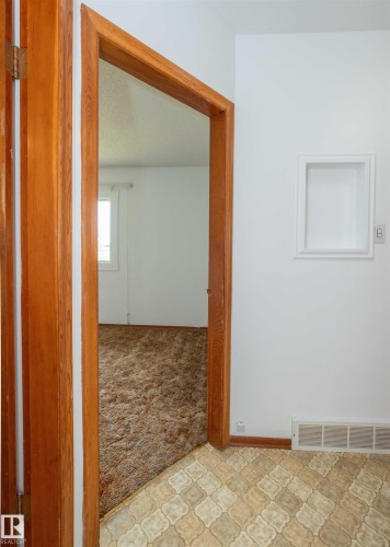 Transitional space featuring wood-finish door frames and baseboards, white painted walls, and a recessed wall niche - 4414 54 Avenue, Barrhead, AB - Indoor Photo Showing Other Room