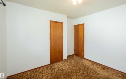 Interior room featuring white walls and two wood-finish doors with round metal knobs - 4414 54 Avenue, Barrhead, AB - Indoor Photo Showing Other Room