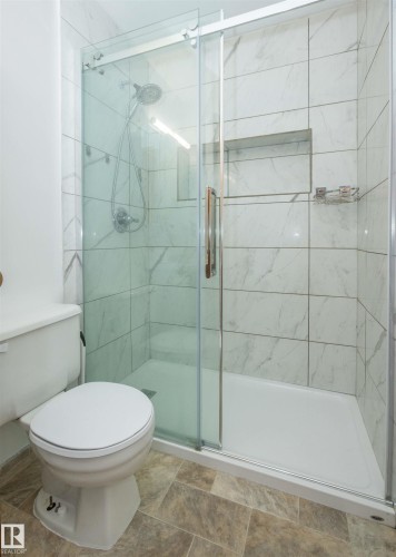 Glass-enclosed shower with white marble-look subway tile and a built-in shower niche - 4414 54 Avenue, Barrhead, AB - Indoor Photo Showing Bathroom