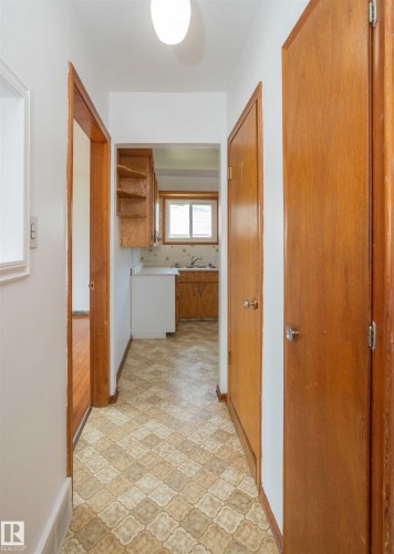 Hallway featuring patterned floor tiles, white walls, and wood-finish doors and trim - 4414 54 Avenue, Barrhead, AB - Indoor