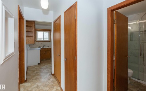 Hallway featuring wood-finish doors, a flush-mount light fixture, and patterned vinyl flooring - 4414 54 Avenue, Barrhead, AB - Indoor