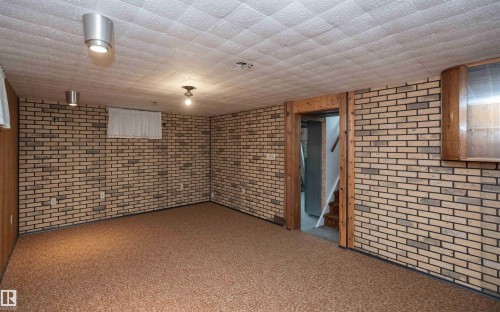 Carpeted room featuring brick-style wall paneling, wood paneling, and a drop ceiling - 4414 54 Avenue, Barrhead, AB - Indoor Photo Showing Other Room