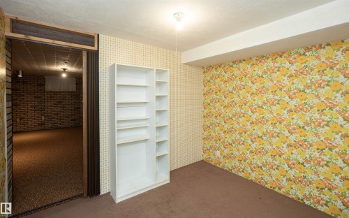 Room featuring a built-in white shelving unit, textured brown carpeting, and a drop ceiling with exposed lighting - 4414 54 Avenue, Barrhead, AB - Indoor Photo Showing Other Room