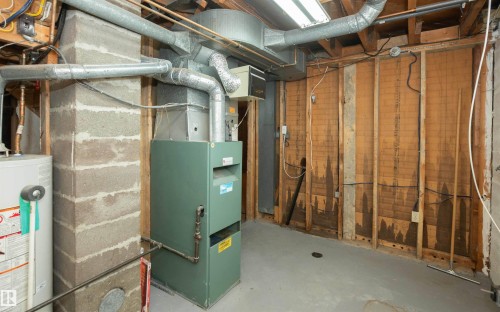 Basement utility area featuring a furnace, water heater, concrete block column, exposed wood framing, and concrete flooring - 4414 54 Avenue, Barrhead, AB - Indoor Photo Showing Basement