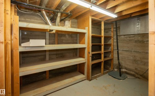 Concrete foundation walls with exposed wood framing and built-in shelving - 4414 54 Avenue, Barrhead, AB - Indoor Photo Showing Basement