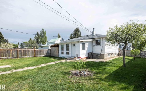 Expansive rear yard featuring mature trees, a manicured lawn, and a wood privacy fence - 4414 54 Avenue, Barrhead, AB - Outdoor