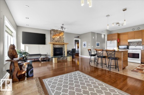 Open-concept living space featuring wood-finish flooring and a stone-clad fireplace with a wood mantle - 5019 48 Avenue, Chipman, AB - Indoor With Fireplace
