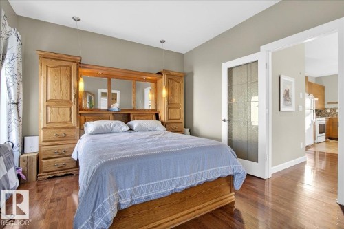 Hardwood-style flooring throughout the room with a frosted glass door and recessed lighting - 5019 48 Avenue, Chipman, AB - Indoor Photo Showing Bedroom