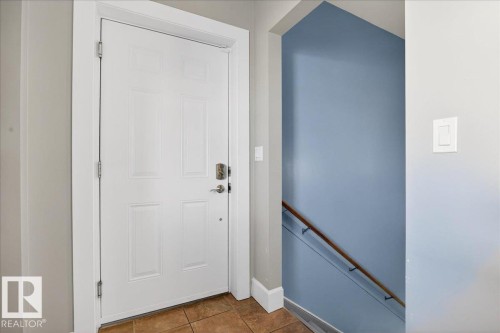 Entryway featuring a paneled door with polished hardware, tile flooring, and a stairway with a wood handrail - 5019 48 Avenue, Chipman, AB - Indoor Photo Showing Other Room
