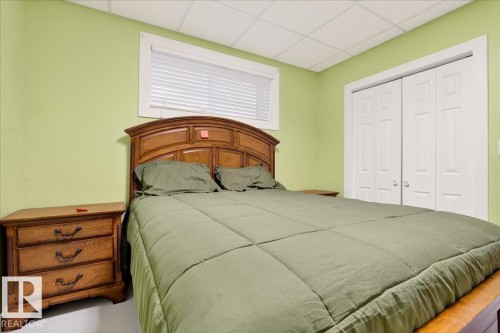 Room featuring light green walls, a window with blinds, and white bi-fold closet doors - 5019 48 Avenue, Chipman, AB - Indoor Photo Showing Bedroom
