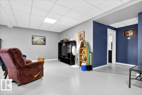 Spacious room featuring light gray walls, a prominent accent wall in a deep blue hue, and a white grid ceiling with integrated lighting - 5019 48 Avenue, Chipman, AB - Indoor Photo Showing Other Room
