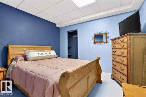 Room featuring a drop ceiling with integrated lighting, two-tone wall paint, a built-in closet with shelving, and light-toned flooring - 5019 48 Avenue, Chipman, AB - Indoor Photo Showing Bedroom