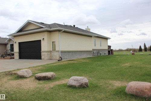 Stucco exterior with stone veneer accents and a dark panel garage door - 5019 48 Avenue, Chipman, AB - Outdoor