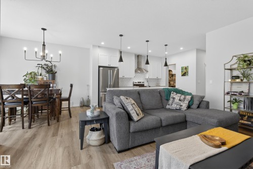 Living room and kitchen area featuring wood-finish flooring, white walls, and recessed lighting - 22836 94 Avenue, Edmonton, AB 
