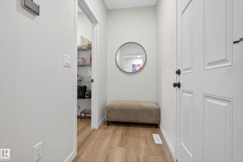 Hallway featuring wood-finish flooring, white walls, and a recessed pantry with wire shelving - 22836 94 Avenue, Edmonton, AB 