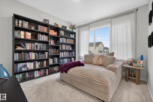 Built-in dark-finish shelving system with expansive storage, light neutral wall paint, large window with natural light, light-toned carpeting, and decorative window treatments - 22836 94 Avenue, Edmonton, AB 