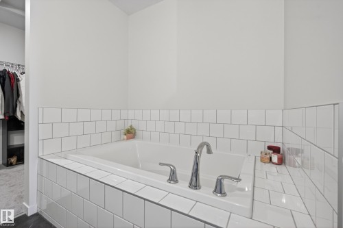 Built-in soaking tub featuring white subway tile surround with contrasting grout, chrome fixtures, and a tiled ledge - 22836 94 Avenue, Edmonton, AB 