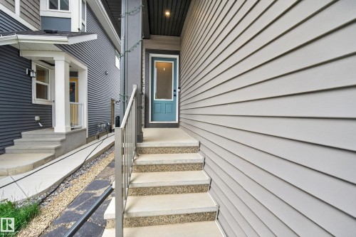 Front entryway featuring a teal door, concrete steps with exposed aggregate treads, and a metal handrail - 22836 94 Avenue, Edmonton, AB 