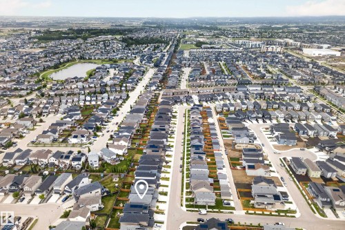 Aerial perspective showcasing a residential development with multiple detached and attached properties, featuring a central water body and extensive green spaces - 22836 94 Avenue, Edmonton, AB 