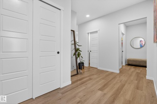Hallway featuring wood-finish flooring, white paneled doors, recessed lighting, and crisp white baseboards - 22836 94 Avenue, Edmonton, AB 