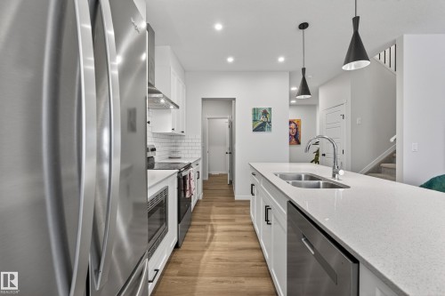 Modern kitchen featuring a large island with dual basin sink and gooseneck faucet - 22836 94 Avenue, Edmonton, AB 