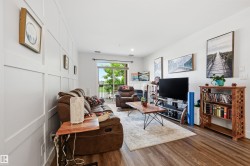 Living area featuring wood-finish flooring, a white paneled accent wall, and a sliding glass door to an outdoor balcony - 