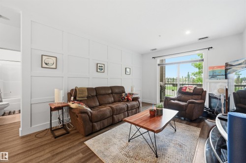 Living area featuring panel accent wall, wood-finish flooring, recessed lighting, and sliding glass door access to an outdoor space - 217 2503 Hanna Crescent, Edmonton, AB 