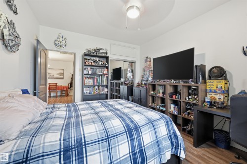 Bedroom with wood-finish flooring, a ceiling fan with integrated lighting, and white walls - 217 2503 Hanna Crescent, Edmonton, AB 